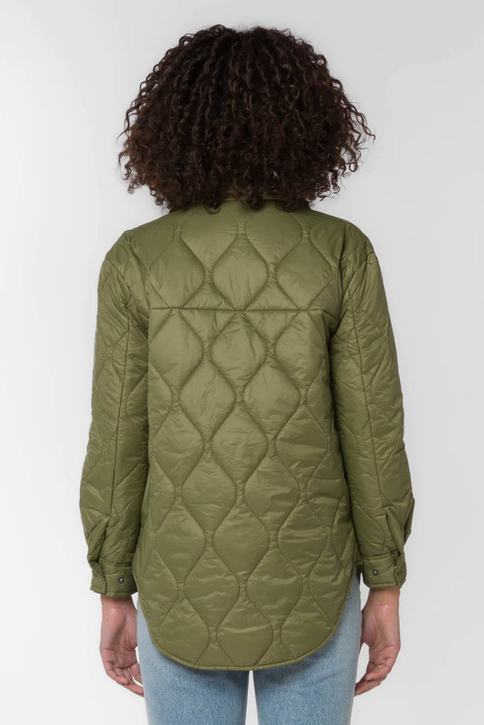 The Eleanor light weight puffer in olive color is crafted from a nylon quilted fabric. It features chest pockets, side seam pockets, snap closure and a dolphin hem for a flattering fit.