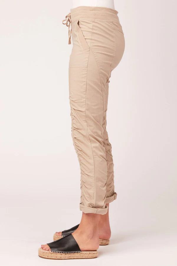 Women's Jules Pant in sand. Simply classic. This pant features drawstring waistband, two front pockets, rouching on pant leg, style lines for added structure, and drawstring at hem. Fabric Content: Stretch poplin body - 96/4 Cotton/Spandex