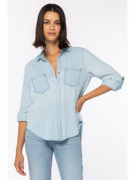 Women's Riley button down shirt in chambray blue. Rolled tab sleeve button down collared shirt, double chest pockets, split back tail.