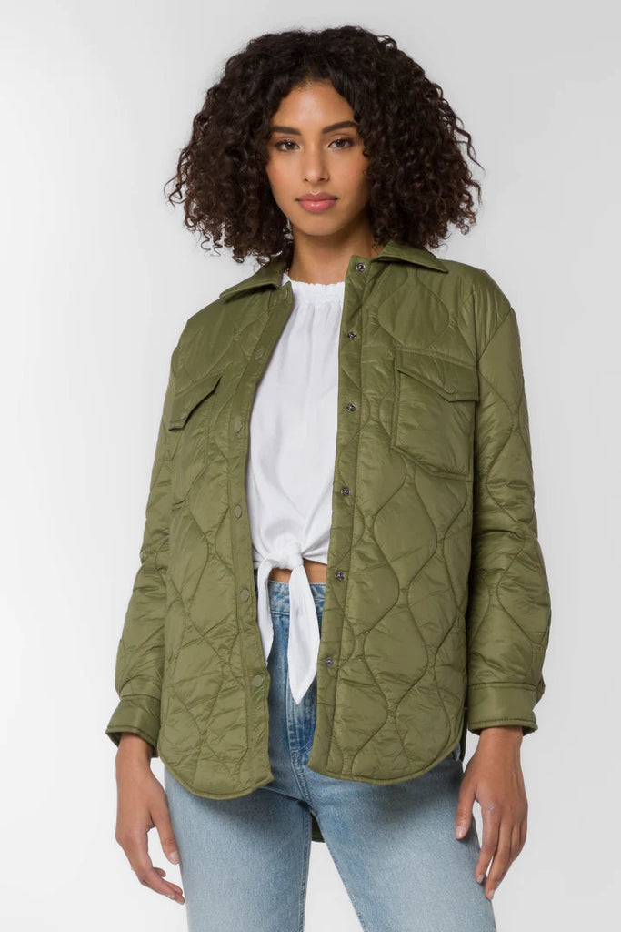 The Eleanor light weight puffer in olive color is crafted from a nylon quilted fabric. It features chest pockets, side seam pockets, snap closure and a dolphin hem for a flattering fit.