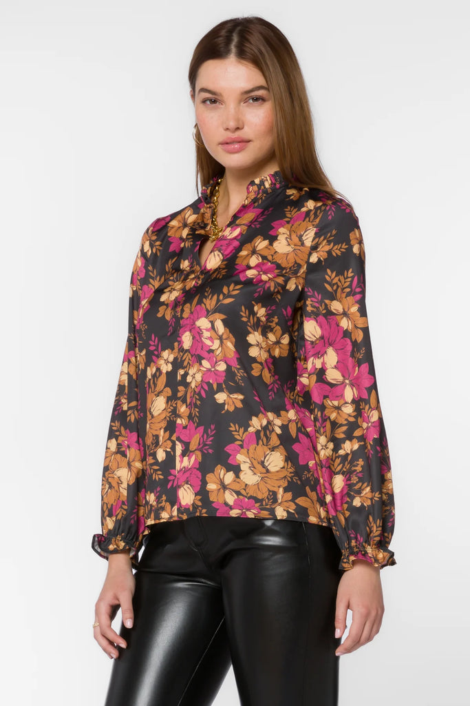 Maggie Blouse in multi gold floral black background features long sleeves, a pop-over design, a split v-neck, a high-low hem, and ruffle details for added style. Its lightweight fabric and flattering fit make this top a great addition to any wardrobe.