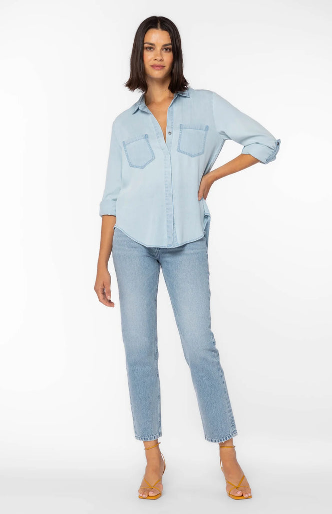 Women's Riley button down shirt in chambray blue. Rolled tab sleeve button down collared shirt, double chest pockets, split back tail.