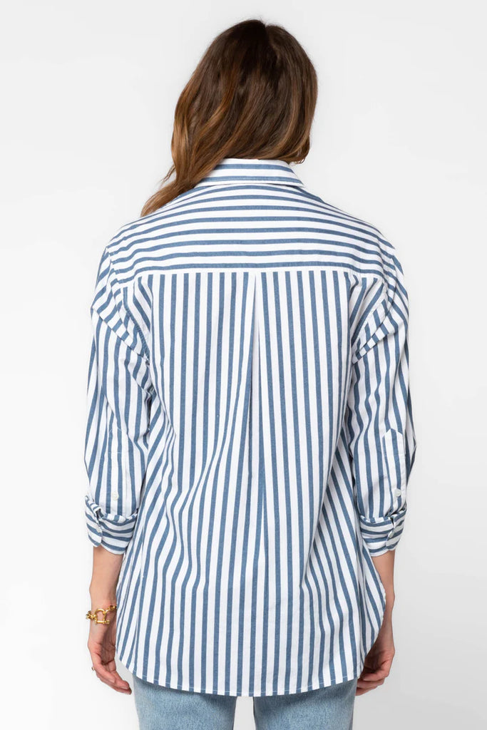 The Suri Shirt is a stylish wardrobe staple. It features long cuffed sleeves, a button-up front, a high-low hem, a back yoke, and a collar for a professional and polished look. Elevate your casual look with this classic design.