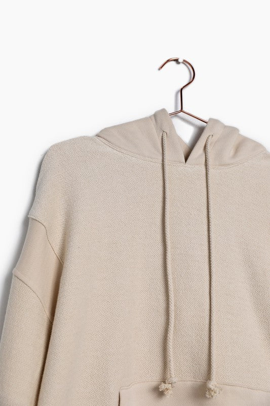 The Davie Sweatshirt in natural color. With a classic hoodie silhouette, this sweatshirt uses contrast reverse terry fabrication for added detail. Features an adjustable hood drawstring and a kangaroo pocket. Fabric Content: 100% Cotton