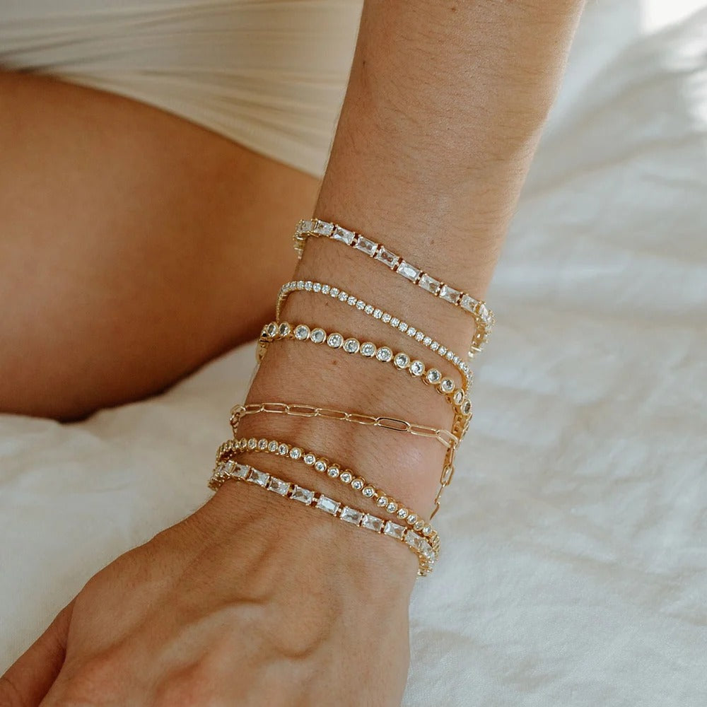  Simple and perfect at the same time! Add this 2mm cz tennis bracelet to any of your stacks for extra shine. 6.5" with a 1" extender 14k Gold plating over brass